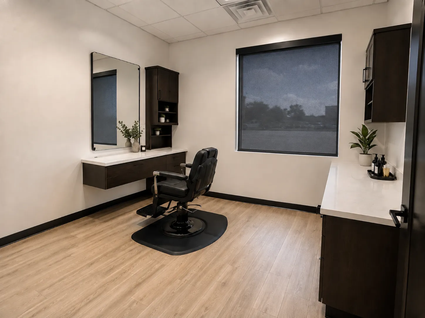 Private salon suite at Houston55 by Paramount Suites with a styling chair, quartz vanity, mirror, and warm wood finishes.
